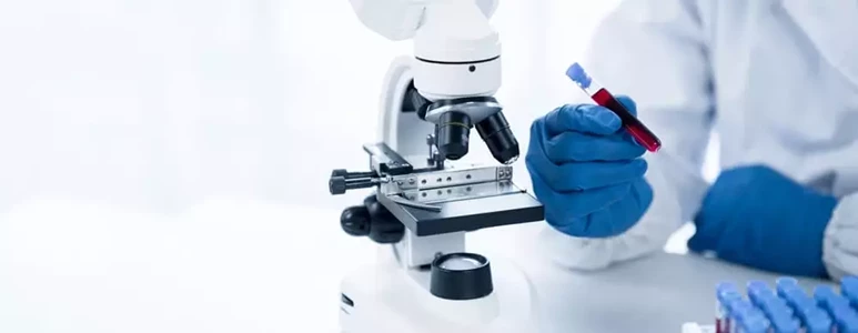 Diagnosta laboratoryjny analizuje krew pod mikroskopem.
