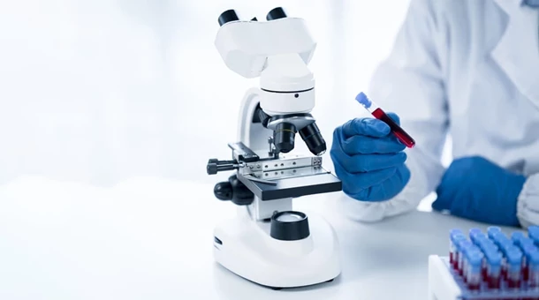 Diagnosta laboratoryjny analizuje krew pod mikroskopem.